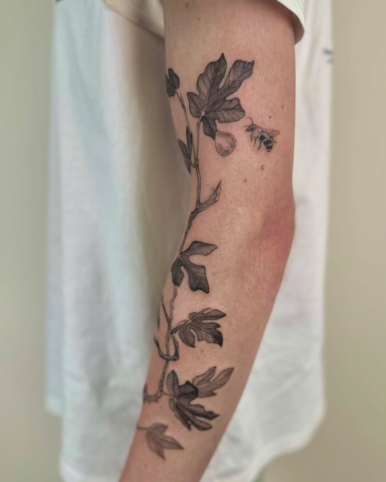 The inside of the forearm, where a bee sits among the fig leaves